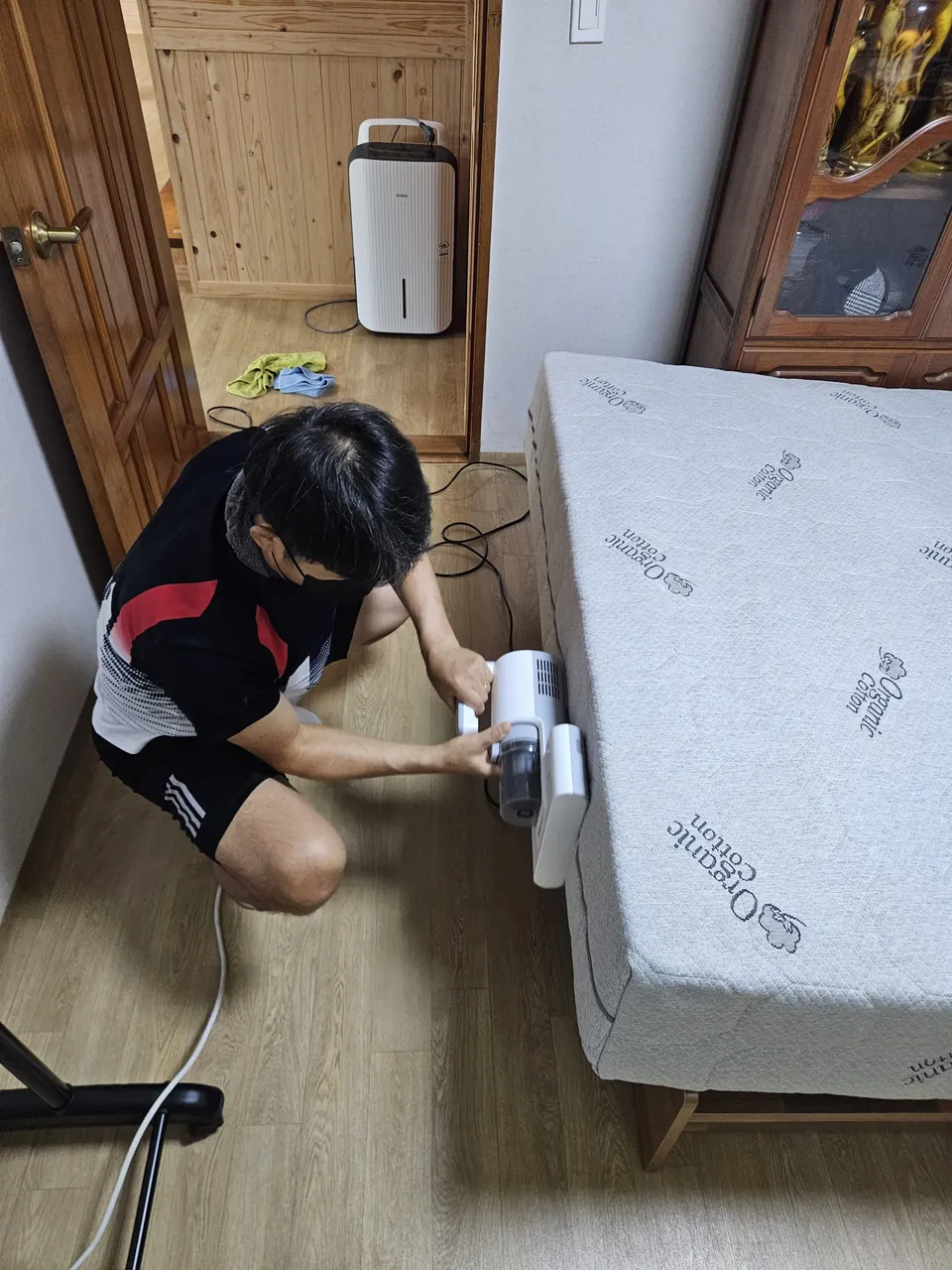 매트리스 옆면 하단을 침구청소기로 흡입하는 모습 — 라텍스 매트리스청소 2단계