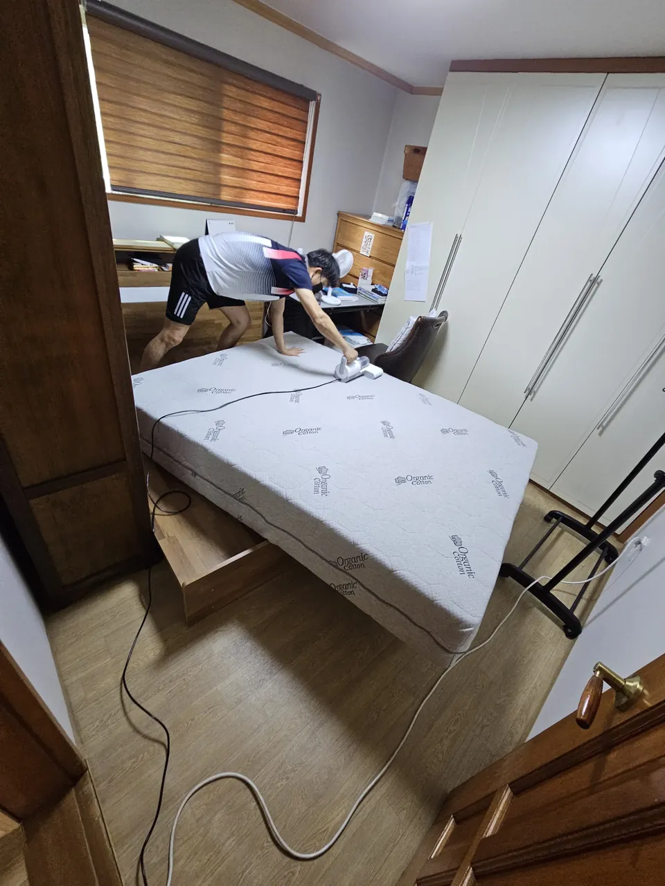 매트리스 한쪽을 들어 올려 하부를 작업하는 모습 — 퀸사이즈 매트리스청소 2단계